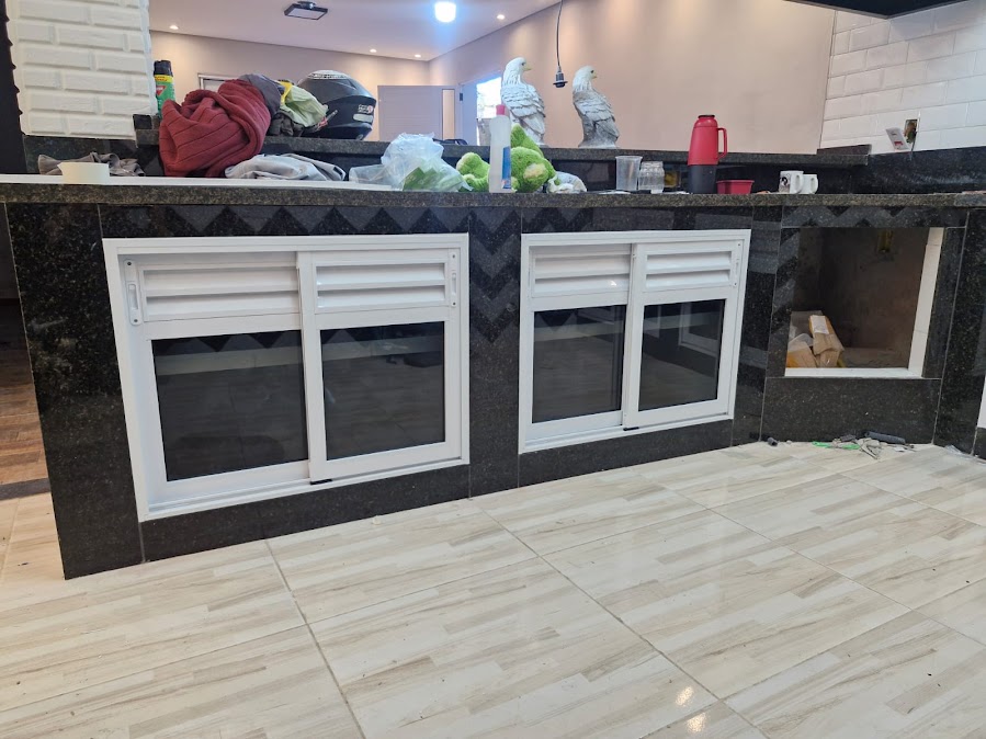 Janela de alumínio branco com persianas integradas em bancada de granito